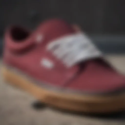 A close-up view of burgundy Vans on a skateboard, showcasing their design and texture.